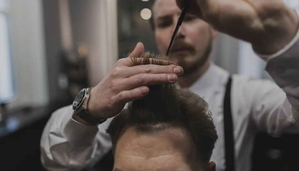 Barbeiro cortando o cabelo com tesoura e pente